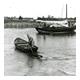 Man in roeiboot en zeilschip in haven van Smit Slikkerveer